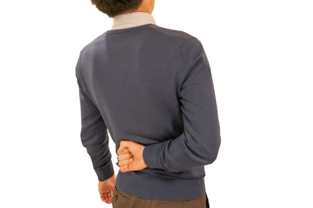 腰に手を当てて痛がる男性 後ろ姿