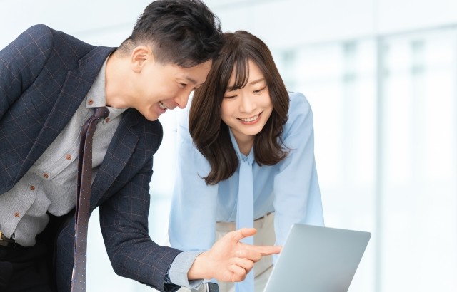パソコン画面を見ながら笑顔で話す男女