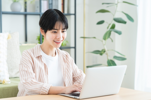 テーブルでノートパソコンを使うショートカットの女性笑顔