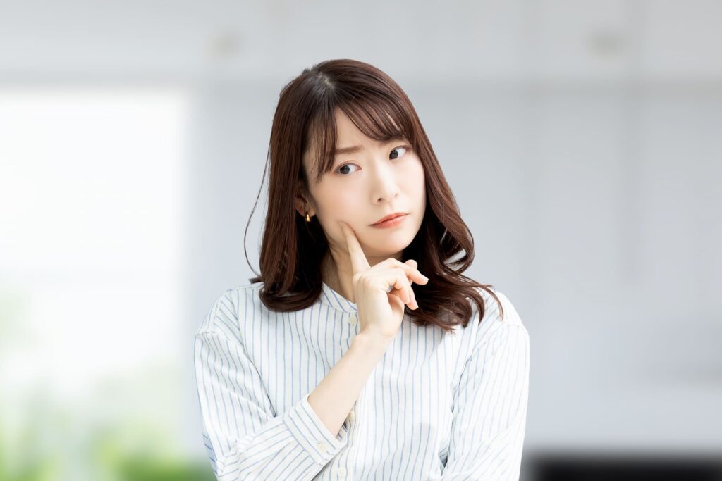 顎に指を当てて考えている女性