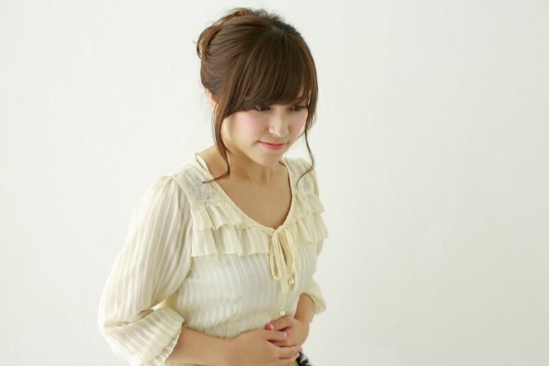 おなかをおさえている女性